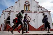 People run past a heavily damaged church in Les Cayes, Haiti, on Aug. 18, 2021, after a 7.2 magnitude earthquake rocked the area four days earlier.