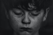 Black-and-white photo of a boy with a tear running down his cheek.