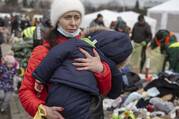 A woman carries her child as she arrives at the Medyka border crossing after fleeing from the Ukraine, in Poland, Monday, Feb. 28, 2022. The head of the United Nations refugee agency says more than a half a million people had fled Ukraine since Russia’s invasion on Thursday. (AP Photo/Visar Kryeziu)