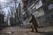 A woman walks past a burning apartment building after shelling in Mariupol, Ukraine, Sunday, March 13, 2022. (AP Photo/Evgeniy Maloletka)