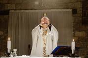 A priest lifts up the consecrated host during Mass.