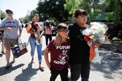 Dora Flores and her grandson arrive at Robb Elementary School in Uvalde, Texas, May 25, 2022, with flowers the day after a mass shooting. (CNS photo/Marco Bello, Reuters)