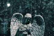 Stock image of a stone statue of an angel surrounded by falling snow.