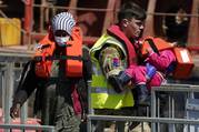 A soldier carries a child from among a group of people believed to be migrants to shore in Dover, England, after a small boat incident in the Channel, on June 14, 2022. (Andrew Matthews/PA via AP)