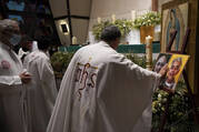 A priest touches the photos of Jesuit priests Javier Campos Morales, left, and Joaquin Cesar Mora Salazar during a Mass to mourn their death, at a church in Mexico City, on June 21, 2022. (AP Photo/Fernando Llano)