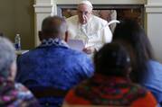 The pope, seated, speaks to a crowd