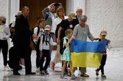 family stands at the vatican holding a ukrainian flag as refugees from the country