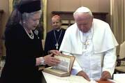 Queen Elizabeth II, dressed in black, opens a book alongside Pope John Paul II