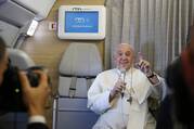 pope gestures in front of a screen on a plane that says welcome on board