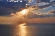 Sunlight peeking through clouds over the ocean.