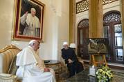 Pope Francis dressed in white garments sits speaking to Sheikh Ahmad el-Tayeb dressed in black with a white hat