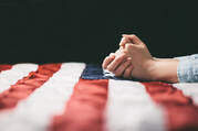 hands praying over USA flag