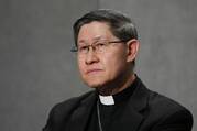 cardinal luis antonio tagle sits with a gray background behind him while wearing his clerics