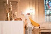 priest holding up eucharist at moment of consecration, during a latin mass