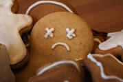 a close up of a gingerbread man with x letters for eyes and a frowny face