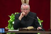 A man in black priest's garb speaks into a microphone