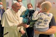 pope francis greets a baby held by his mother