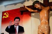 A crucifix in front of a poster of Chinese President Xi Jinping.