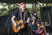 A smiling Willie Nelson playing his guitar Trigger at a recent concert. 