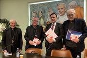 Three Catholic priests and a man in a suit pose for a photo