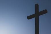 Black cross statue on blue background