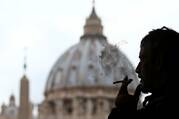 a silhouette of a man smoking in front of the vatican