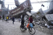 Palestinians walk by the destroyed building of Al Nuseirat Bakery in an Israeli airstrike Nusseirat refugee camp Gaza Strip, Wednesday, Oct. 18, 2023. (AP Photo/Hatem Moussa)