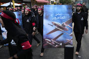 Members of Iranian-backed Hezbollah group walk barefoot as they carry a poster showing Hezbollah drones that read, in Arabic: "We are coming," during the holy day of Ashoura, which commemorates the 7th century martyrdom of the Prophet Muhammad's grandson Hussein, in the southern suburb of Beirut, Lebanon, Tuesday, Aug. 9, 2022. (AP Photo/Hussein Malla, File)