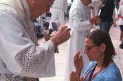 A pilgrim crosses herself after receiving Communion on her knees July 20, 2024, at Lucas Oil Stadium in Indianapolis during the National Eucharistic Congress. (OSV News photo/Bob Roller)