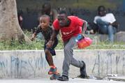 A man and child take cover from gunfire near the National Palace in Port-au-Prince, Haiti, March 21, 2024. (OSV New photo/Ralph Tedy Erol, Reuters)