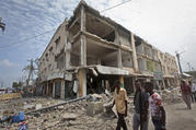 Men walk near destroyed buildings as thousands of Somalis gathered to pray at the site of the country's deadliest attack and to mourn hundreds of victims at the site of the attack in Mogadishu, Somalia, on Oct. 20. (AP Photo/Farah Abdi Warsameh)