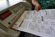 In Phoenix, Az., a Maricopa County Elections official feeds a ballot into a machine during a training session on Oct. 25. (AP Photo/Matt York)