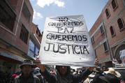A supporter of former President Evo Morales holds a sign with a handwritten message that reads in Spanish: "We don't want peace, We want justice," during a protest at a blocked highway in El Alto, on the outskirts of La Paz, Bolivia, Wednesday, Nov. 20, 2019. (AP Photo/Natacha Pisarenko)