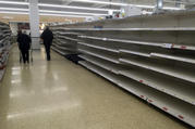 Shoppers walk past empty shelves in a supermarket in Rugby, England, Thursday, March 19, 2020. Supermarkets are limiting the number of similar items shopper can buy to try and halt hoarding and panic buying. According to the World Health Organization, most people recover in about two to six weeks, depending on the severity of the illness. (AP Photo/Martin Cleaver)