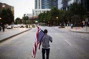 Skylar Barrett walks with an American flag in the middle of the street during a march through the Buckhead neighborhood against the recent police shootings of African-Americans on Monday, July 11, 2016, in Atlanta. (AP Photo/David Goldman)
