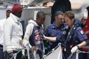Italian coast guards instruct immigrants as they disembark from a coast guard ship at port in Lampedusa, Italy