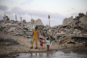 Palestinians in Gaza walk next to the ruins of houses destroyed during the Israeli offensive. (CNS photo/Ibraheem Abu Mustafa, Reuters)