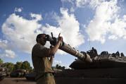 An Israeli soldier adjusts the barrel of a tank at a military staging area outside the northern Gaza Strip on July 14. 