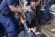 Hungarian policemen detain migrants on the tracks at a railway station in the town of Bicske, Hungary, Sept. 3. (CNS photo/Laszlo Balogh, Reuters)