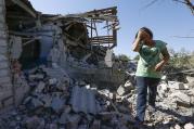 A woman walks at her destroyed house in the village of Kominternovo, Ukraine, near the southern coastal town of Mariupol in September. (CNS photo/Vasily Fedosenko, Reuters) 