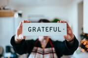 person holding white and black 'grateful' card