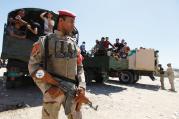 ON GAURD. An Iraqi soldier stands before truckloads of volunteers in Baghdad on June 17, eager to fight Sunni militants converging on the city. 