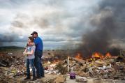 A father hugs his daughter while taking a break from helping friends sift though rubble from homes destroyed in an Arkansas tornado.