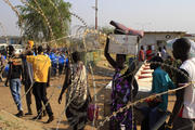 People walk past razor wire Jan. 7 at Tomping camp, where thousands of displaced people who fled their homes are sheltered by the United Nations near Juba, South Sudan. (CNS photo/James Akena, Reuters)
