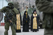 Orthodox clergymen pray near armed servicemen outside Ukrainian border guard post. (CNS photo/Baz Ratner, Reuters)