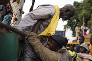 Priest helps a Muslim man climb down from an open truck in Central Africa Republic. (CNS photo/Siegfried Modola, Reuters)