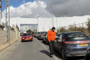 Palestinian sells souvenirs to cars passing through checkpoint at Israeli separation wall in Bethlehem.