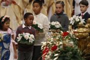 Children carry flowers to place at a figurine of the baby Jesus as Pope Francis celebrates Christmas Eve Mass in St. Peter's Basilica at the Vatican on Dec. 24. (CNS photo/Paul Haring)