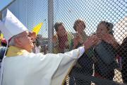 Bishop Mark J. Seitz of El Paso, Texas, touches the hands of people in Mexico through a border fence following Mass in Sunland Park, N.M., in this 2014 file photo. (CNS photo/Bob Roller)