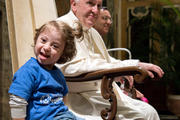 A young girl sitting next to Pope Francis smiles during an audience with Special Olympics athletes participating in the Unified Football tournament, at the Vatican Oct. 13. (CNS photo/L'Osservatore Romano)